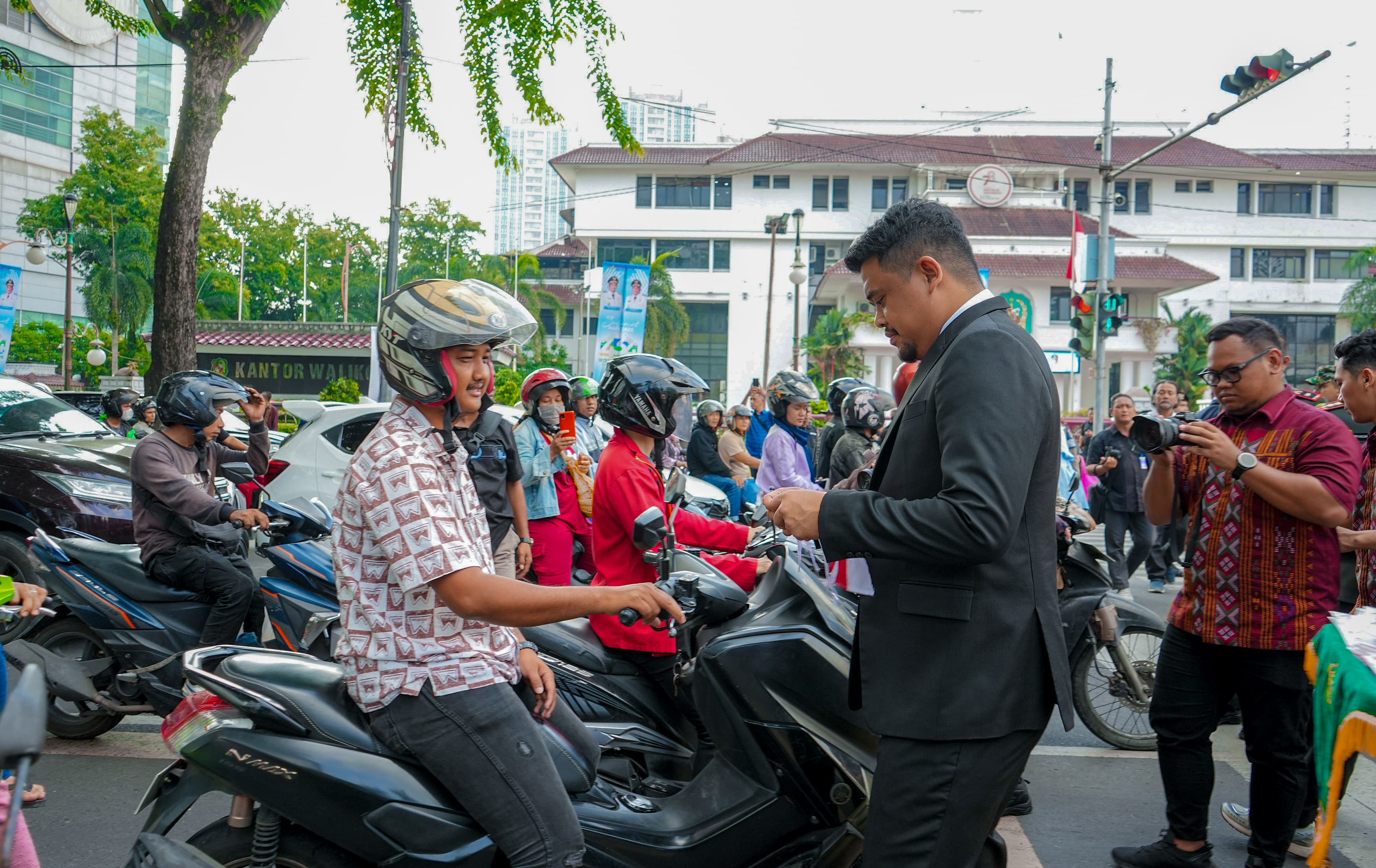 Wali Kota Medan, Bobby Nasution, Membagi-Bagikan Bendera Merah Putih Kepada Pengendara Yang Melintas di Depan Kantor Wali Kota, Jalan Kapten Maulana Lubis, Kecamatan Medan Petisah